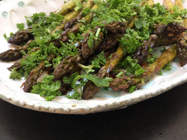 White china plate full of asparagus and herbs