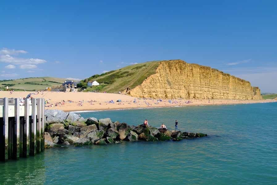 West Bay beach with sea, sand and tall cliff