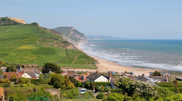 Charmouth village image of houses, grassy hill, beach and sea